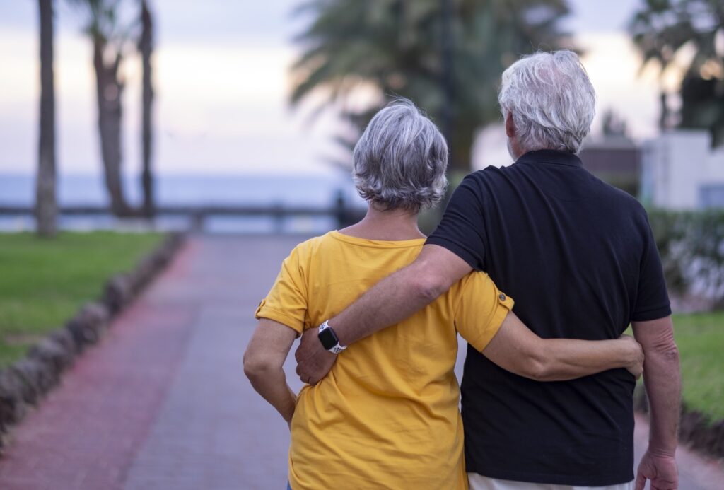 Rear view of two senior people walking happy enjoying their retirement and beach vacation